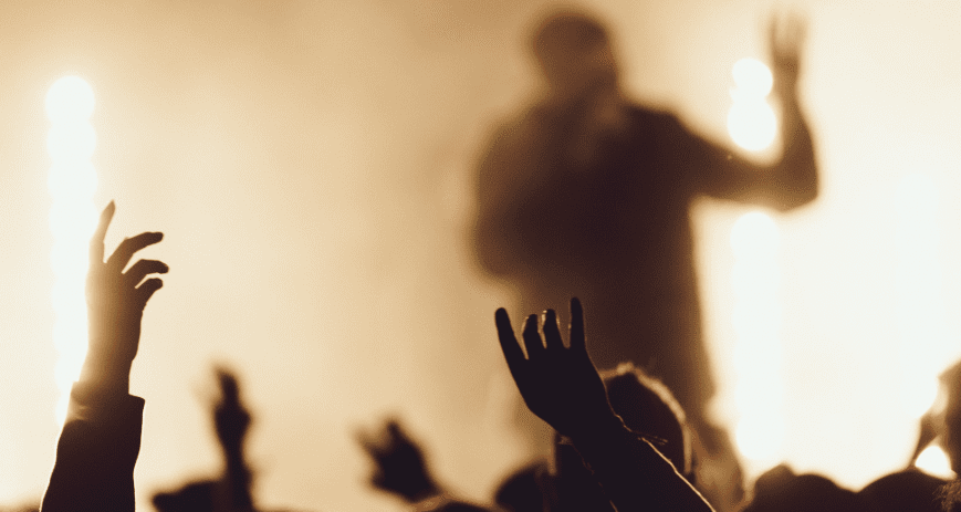 Homályos kép egy koncertről, elmosódva lástzik az énekes, és a kezek a magasban
